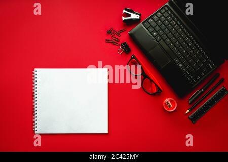 Home Office. Büroarbeitsplatz mit Laptop, Notebook, Bürobedarf und Schreibwaren auf dunkelrotem Hintergrund. Lösung, Geschäftsplanung, kreativ, desi Stockfoto