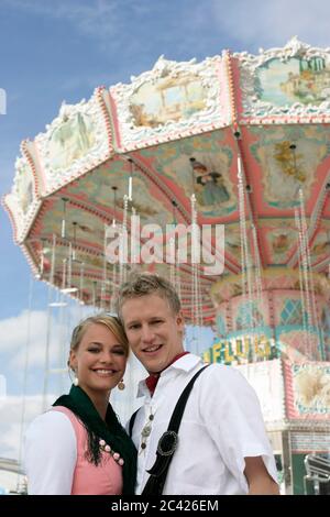 Das junge Paar hat sich vor einem Kettenkarussell fotografieren lassen - Oktoberfest - München - Wiesn Stockfoto