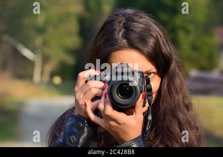 Lady Fotograf mit DSLR-Kamera in der Natur über grünen Bokeh Hintergrund, horizontale Ausrichtung Stockfoto