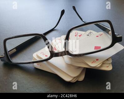 Brille und Deck von Pokerkarten auf dem Tisch als Symbol für das Glücksspiel. Isolation von Innenräumen, da soziale Distanzierung Quarantänemaßnahmen Goi einschränken Stockfoto