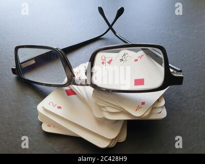 Brille und Deck von Pokerkarten auf dem Tisch als Symbol für das Glücksspiel. Isolation von Innenräumen, da soziale Distanzierung Quarantänemaßnahmen Goi einschränken Stockfoto