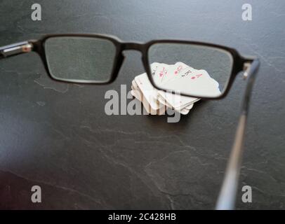 Brille und Deck von Pokerkarten auf dem Tisch als Symbol für das Glücksspiel. Isolation von Innenräumen, da soziale Distanzierung Quarantänemaßnahmen Goi einschränken Stockfoto