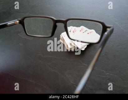 Brille und Deck von Pokerkarten auf dem Tisch als Symbol für das Glücksspiel. Isolation von Innenräumen, da soziale Distanzierung Quarantänemaßnahmen Goi einschränken Stockfoto