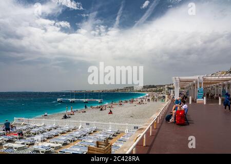 Nizza, Frankreich - 14. Juni 2019 : Touristen genießen ihren Tag am Strand von Nizza, an der französischen riviera, mit der Promenade des Anglais. Stockfoto