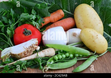 Verschiedene Gemüsesorten, Tomaten, Zwiebeln, Kartoffeln, Sellerie, Personley, Erbsen, Meerrettich, Karotten auf Holzgrund Stockfoto