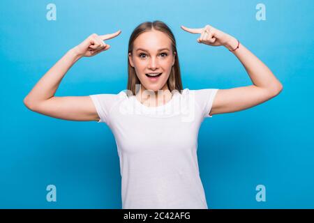 Junge Frau, die über blauem Hintergrund lächelnd mit beiden Händen Finger auf den Kopf zeigt, große Idee oder Gedanken, gute Erinnerung Stockfoto