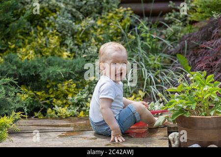 Kleiner Junge weint auf dem Holztisch im Garten. Stockfoto