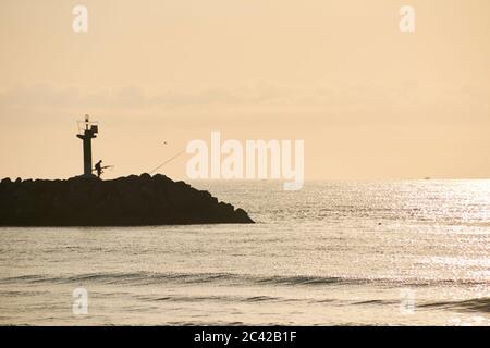 Fischer, die entlang der groyne Sonnenaufgang, Silhouetten, Leuchtturm, Boote Stockfoto