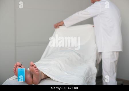 Doktor bedeckt tote Frau mit einem Laken Stockfoto