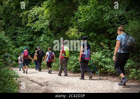 Calcata (VT), Italien - 13. Juni 2020: Gruppe von Wanderern geht den Weg in den Wald. Die Menschen gehen in einer Reihe und tragen technische Kleidung und spezielle st Stockfoto