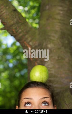 Junge Frau balanciert Apfel auf ihrem Kopf Stockfoto