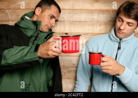 Der Mensch hält einen Becher und ein anderer einen Krug in der Hand Stockfoto