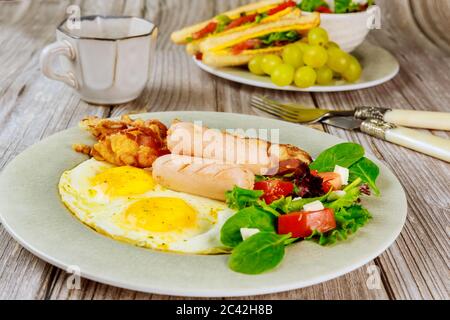 Leckeres Frühstück mit Eiern, Würstchen, Speck, Toast und einer Tasse Kaffee. Stockfoto
