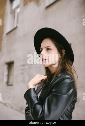 Profilporträt einer jungen Frau mit schwarzem Hut und Leder Jacke Stockfoto