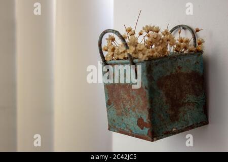 Bündel von blechenden künstlichen Blumen, Heu gefärbt, in einem blauen Metallkasten, sehr alt und verrostet, an der Wand hängen Stockfoto