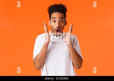 Beeindruckt, erschrocken afrikanisch-amerikanischer Kerl, der etwas tolles sieht, verwundert und amüsiert, Rabatte beim Auschecken, Saisonverkauf, atemberaubend beiwohnen Stockfoto