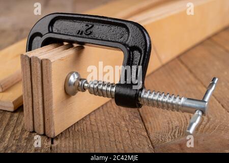 Schreinerei Klemme zum Kleben von Holz verwendet. Tischlerzubehör in einer Hauswerkstatt. Arbeitsplatz - Schreinerei Werkstatt. Stockfoto