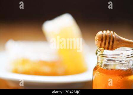 Frischer Honig süß in Glas Glas mit Holzdipper / Wabe, Honig Biene Hintergrund Stockfoto