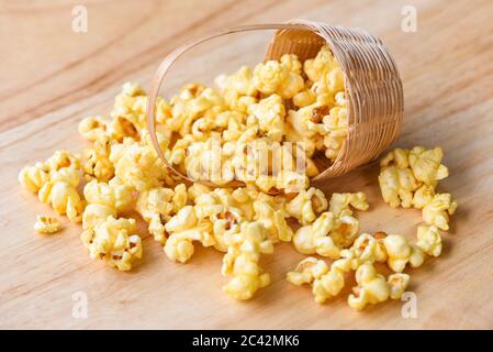 Popcorn in Holzkorb und Holz backgroubd / Süße Butter Popcorn Salz Stockfoto