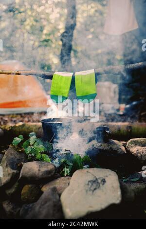 Trocknen nasser Socken am Lagerfeuer beim Camping. Socken trocknen im Feuer. Aktive Erholung im Wald. Abenteuer Stockfoto