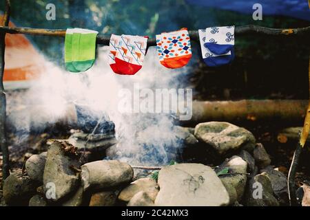 Trocknen nasser Socken am Lagerfeuer beim Camping. Socken trocknen im Feuer. Aktive Erholung im Wald. Abenteuer Stockfoto