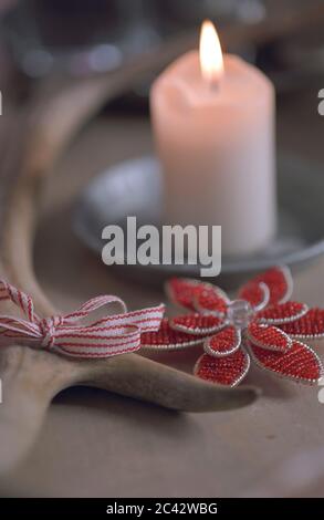Eine Mistelblume aus Perlen neben einer Kerze - Weihnachten Stockfoto