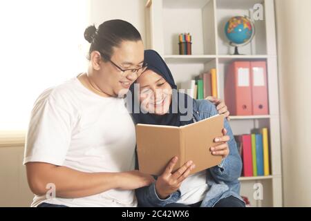 Junge asiatische muslimische Paar Buch zusammen lesen, glücklich fröhlichen Ausdruck, neue verheiratet Planung ihrer Zukunft Konzept Stockfoto