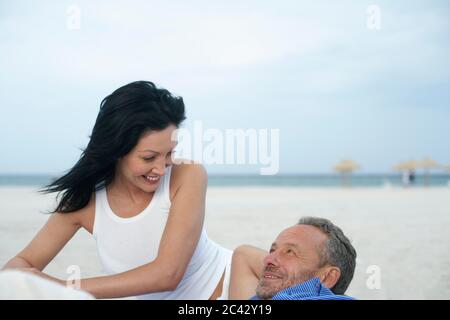 Pärchen mittleren Alters am Strand gelegen Stockfoto