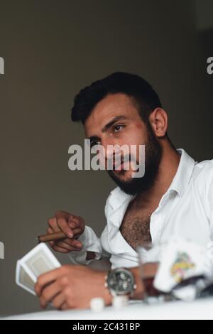 Porträt eines erfahrenen Spielers. Junger Mann, der Zigarre und Whisky trinkt. Stockfoto