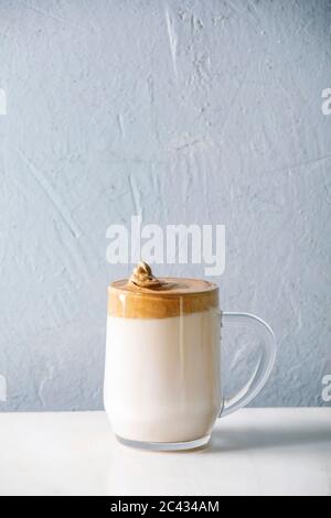 Dalgona schaumig Kaffee Trend koreanisch trinken Milch Latte mit Kaffee Schaum in Glas Becher auf weißem Marmor Tisch. Kopierbereich Stockfoto