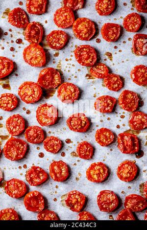 Sonnengetrocknete Kirschtomaten mit Olivenöl und Balsamico-Essig auf Backpapier. Draufsicht, Hintergrund Essen Stockfoto