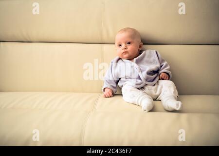 Kleinkind sitzt auf einem Sofa - Nachwuchs - Mimik Stockfoto