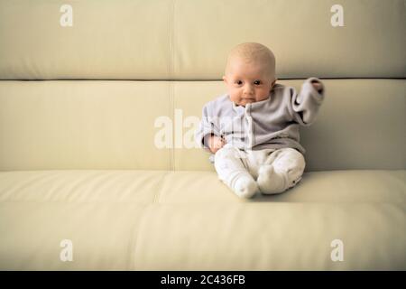 Kleinkind sitzt auf einem Sofa - Nachwuchs - Mimik Stockfoto