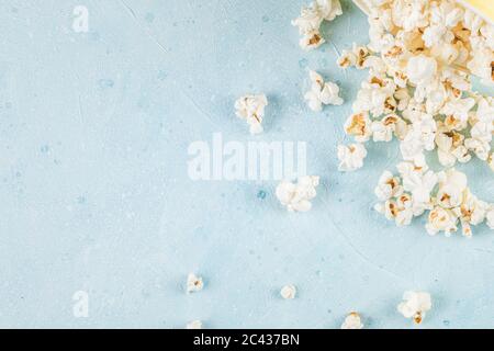 Frische Popcorne verteilen sich auf dem blauen Tisch in der rechten Ecke Stockfoto