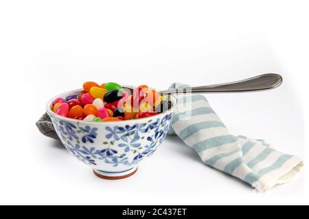 Eine kleine Suppenschüssel mit bunten Jelly Beans und einem Löffel, als ob als Mahlzeit auf Weiß isoliert gegessen Stockfoto