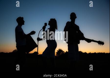 Cloppenburg, Deutschland. Juni 2020. Die Silhouetten der Mitglieder der Band 'Crackerjacks' ragen bei Sonnenuntergang vom Himmel ab. Kurz zuvor hatte die Band ein Ballonkonzert über Cloppenburg. Kredit: Mohssen Assanimoghaddam/dpa/Alamy Live Nachrichten Stockfoto