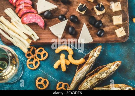 Pepperoni-Scheiben, Käse und schwarze Oliven mit trockenem Fisch und Crackern serviert Stockfoto
