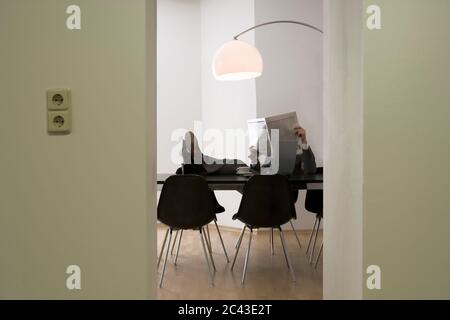 Geschäftsmann in einem schwarzen Stuhl liest den finanziellen Teil einer Zeitung - Warteraum Stockfoto