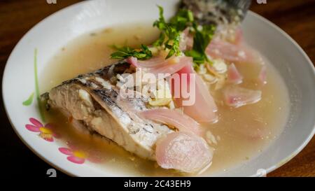 Gedünsteter Rohu-Fisch in Zitronensauce mit roter Zwiebel und garniert mit Koriander. Stockfoto