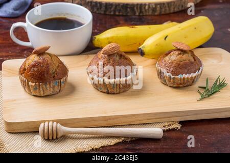 Bananenkuchen auf Holzbrett mit Banane und Kaffee zum Frühstück Stockfoto