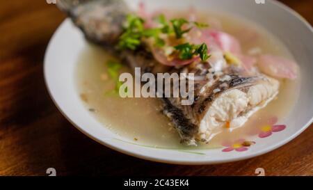 Gedünsteter Rohu-Fisch in Zitronensauce mit roter Zwiebel und garniert mit Koriander. Stockfoto