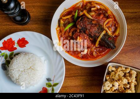 Gebratener Silberwels, gekocht mit würzigem Sambal-Chili und Zwiebel mit Vogelaugen-Chili als Garnierung. Serviert mit Reis und Beilagen. Stockfoto