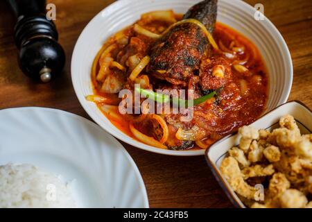 Gebratener Silberwels, gekocht mit würzigem Sambal-Chili und Zwiebel mit Vogelaugen-Chili als Garnierung. Serviert mit Reis und Beilagen. Stockfoto