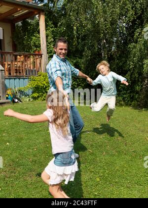 Vater spielt mit Kindern im Garten, München, Bayern, Deutschland Stockfoto