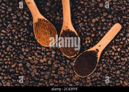Gemahlener Kaffee in einem Löffel auf dem Hintergrund, geröstete Kaffeebohnen Stockfoto