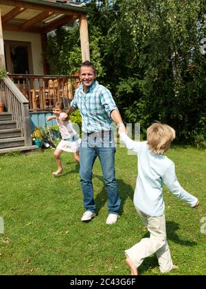 Vater spielt mit Kindern im Garten, München, Bayern, Deutschland Stockfoto