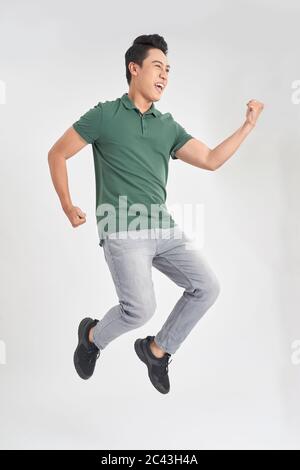 Ganzlänge Foto von lustigen Mann 30er Jahre in lässigen T-Shirt und Jeans laufen oder springen in Luft isoliert auf weißem Hintergrund Stockfoto