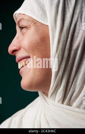 Lächelnde Frau mit Kopftuch schaut zur Seite Stockfoto
