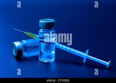 Impfstoffe, Botulinumtoxin und Insulinampullen – Konzeptthema mit Glasfläschchen mit klarer Flüssigkeit neben einer Spritze und einer auf b isolierten hypodermischen Nadel Stockfoto