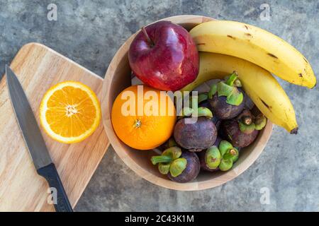 Schneiden orange auf Holzbrett mit Multi-Obst in Holzschale frome Draufsicht. Stockfoto